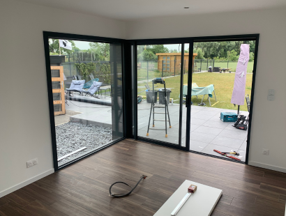 Photographie de l'interieur d'une extension de maison une baie vitrée en angle