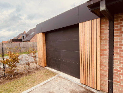 Photographie d'une extension de maison pour réalisé un garage, avec porte de garage noir et bardage mixte, aluminium et bois