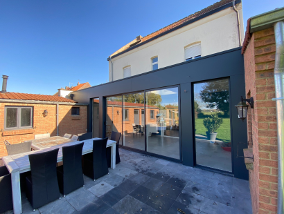 Photographie d'une extension de maison avec bardage noir devant une maison ouvrière du nord