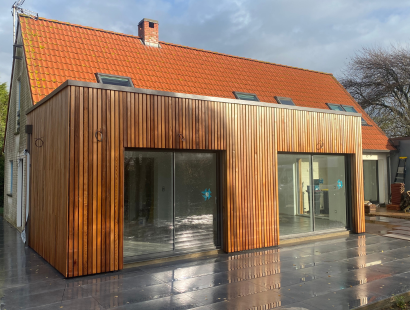 Photographie d'une extension de maison avec bardage en bois sur une terrasse en pierre grise