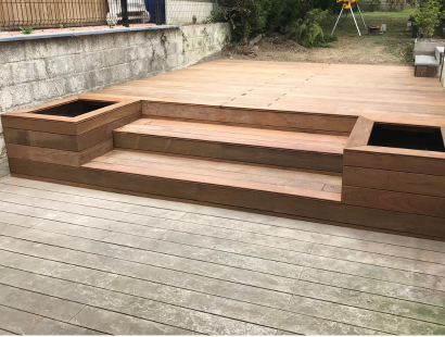 Photographie d'une photo de terrasse en bois sur mesure avec deux pots de fleur intégrés